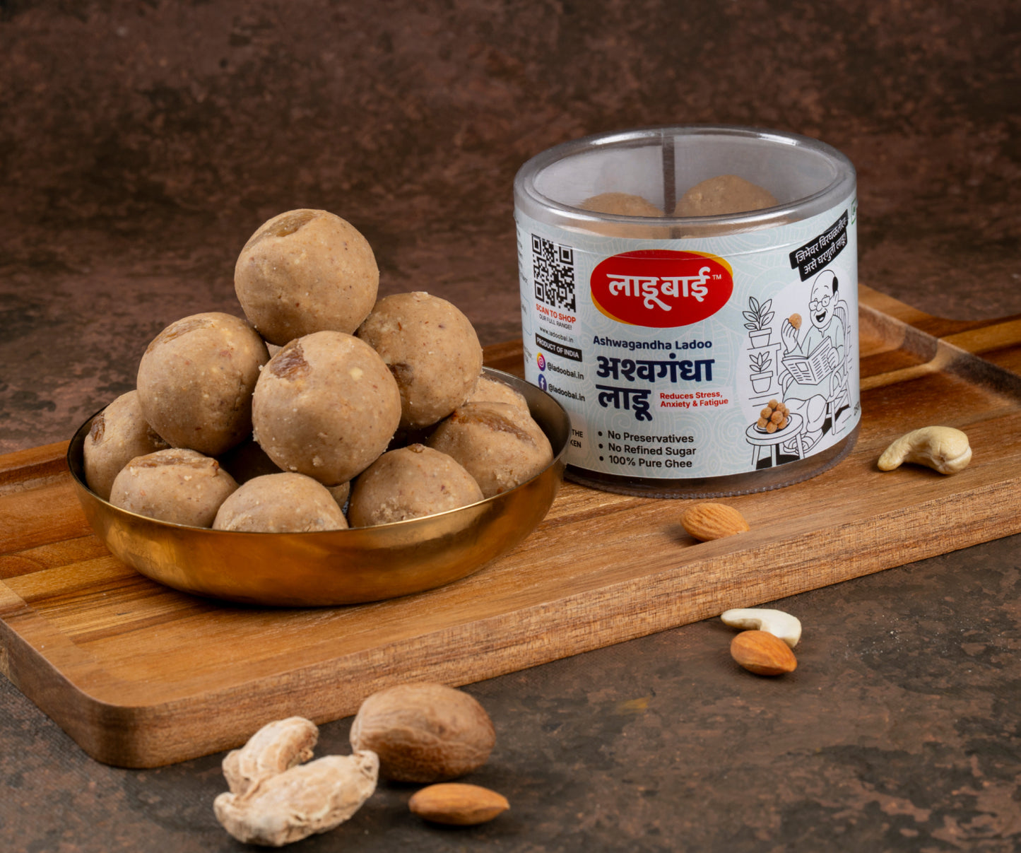 Ashwagandha Ladoo / Balls in a copper bowl with a container labeled 'Ashwagandha Ladoo' and Ladoobai's Brand on a wooden board.
